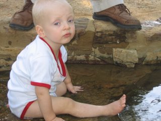 Matthew sitting in a small stream with a bored expression on his face