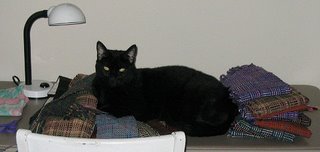 Rascal, making himself at home on my neat pile of handwoven log cabin scarves.