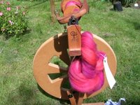 spinning wheel with red fibre , in the garden