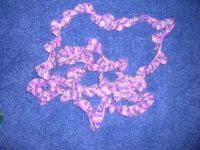  image of narrow crocheted spiral scarf in pink and gray angora yarn - scarf coiled up and photographed against blue carpet