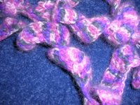 close up image of narrow crocheted spiral scarf in pink and gray angora yarn