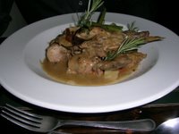 white plate with cooked rabbit and variety of vegetables.
