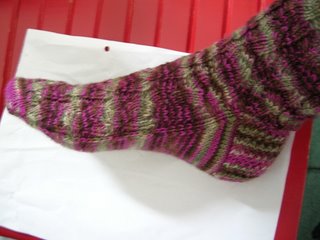 crappy pic of gorgeous handknitted sock - browns, pinks, greens against background of white piece of paper and red chair