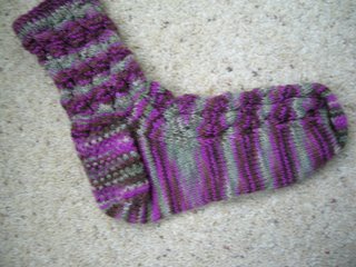 photot of one handknit sock in pinks, browns, greens