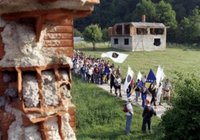 People carrying Bosnian flags pass by destroyed house during the second day of a four-day march to Srebrenica, in the village of Liplje near Zvornik, 120 km (75 miles) north of Sarajevo on Saturday, July 8, 2006. Hundreds of Bosnians began a four-day march on Friday along the route survivors used 11 years ago to escape the Bosnian Serb killings in Srebrenica, the worst massacre in Europe since World War II. (AP Photo/Amel Emric)
