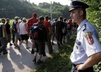 A Bosnian Serb policeman secures people during the second day of a four-day march to Srebrenica in the village of Liplje near Zvornik, 120 km (75 miles) north of Sarajevo Saturday, July 8, 2006. Hundreds of Bosnians began a four-day march on Friday along the route survivors used 11 years ago to escape the Bosnian Serb killings in Srebrenica, the worst massacre in Europe since World War II. (AP Photo/Amel Emric)