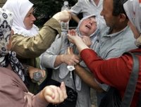 A Bosniak (Bosnian Muslim) women from Srebrenica reacts as trucks carrying 505 victims of the Srebrenica massacre pass down the main street in Sarajevo, Saturday, July 8, 2006. The trucks loaded with the coffins of the newly identified victims of Europe's worst massacre since World War II stopped for a few moments in Sarajevo on Saturday to allow hundreds of people to pay tribute to their beloved ones. The bodies will be buried at Srebrenica on the 11th anniversary of the massacre on Tuesday. (AP Photo/Hidajet Delic)(AP Photo/Hidajet Delic)