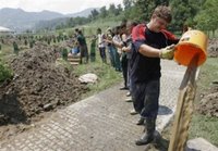 Bosnian workers removing water from the graves after the heavy rain hit the cemetery at the Memorial Center Potocari, near Srebrenica north of Bosnian capital Sarajevo, on Sunday, July 9, 2006. Newly identified bodies will be buried in Srebrenica on Tuesday (July 11th) during the 11th anniversary commemorations of the massacre. Serb troops killed over 8,000 Bosniak men and boys at Srebrenica in 1995. (AP Photo / Amel Emric)