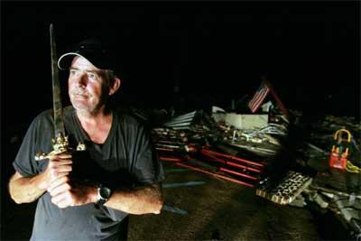 Don Taylor brandishes a sword to ward off looters at the Biloxi pawn shop he was hired to guard after it was destroyed by Hurricane Katrina (foto: Joe Raedle - Getty Images)