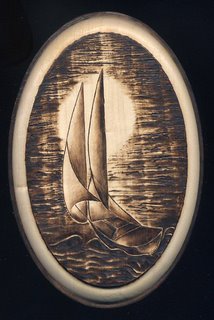 Sailing.  Pyrographic of a sailboat on a wood oval.
