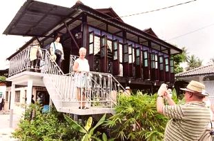 PICTURE PERFECT: A foreign tourist posing in front of a typical stilt Malay house in Kampung Jalan Baru in Balik Pulau after the launch of the homestay programme on Saturday. Cooking demonstrations were also held to show the tourists how to prepare rendang, lemang and traditional cakes. 