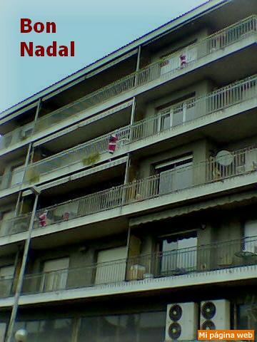 Tres muñecos trepan por la fachada de un edificio de viviendas. Feliz Navidad