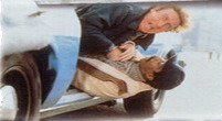 Richard Pryor está com o corpo para fora de um carro em movimento, caindo de costas. Gene Wilder está sobre ele, segurando-o, olhando o movimento assustado e também com boa parte do corpo fora do carro.