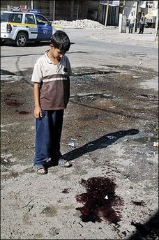 An Iraqi boy looks at a stain of blood at the site where a roadside bomb targeted an Iraqi police patrol, in central Baghdad.