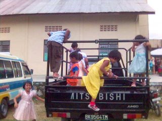 Anak-anak SM bermain di atas mobil di samping gereja. Bosan dengar khotbah ya?