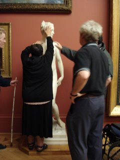 A woman touching the head of a sculpture of a young nude woman