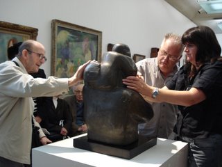 Ken touching the woman and child sculpture