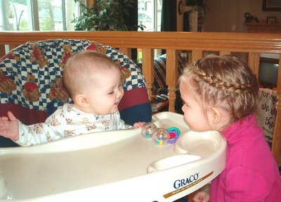 MM and Baby E laughing at each other over the highchair tray