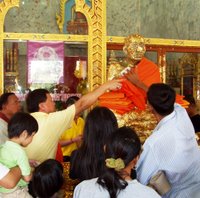 Wat Chalong - locals apply gold leaf to the images