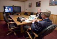 President George W. Bush is handed a map by Deputy Chief of Staff Joe Hagin, center, during a video teleconference with federal and state emergency management organizations on Hurricane Katrina from his Crawford, Texas ranch on Sunday August 28, 2005. White House photo by Paul Morse.