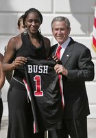 President George W. Bush stands with Crystal Langhorne, captain of the University of Maryland Women's Basketball Team, during a South Lawn ceremony honoring the 2005 and 2006 NCAA champions Thursday, April 6, 2006. The University of Maryland also won national titles in women's field hockey and men's soccer. White House photo by Paul Morse.