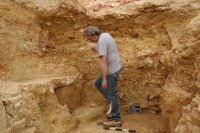 Caption: UNC Charlotte archaeologist James Tabor standing in the partially excavated corridor at the cliff face. Framing him above is what appears to be an archway filled with dirt. Credit: UNC Charlotte, Usage Restrictions: None.