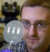 Brian D. Iverson, a mechanical engineering doctoral student at Purdue, holds up a disk containing several 'micro-pump' cooling devices small enough to fit on a computer chip. The tiny pumps circulate coolant through channels etched into the chip. (Purdue News Service photo/David Umberger)