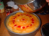 pouring the cool gelatin on top of assembled cake-pudding-fruits