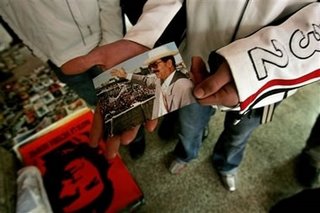 Picture: a "Palestinian" holds a photo of Saddam in mourning, while on the floor is the black-and-red Ché imprint