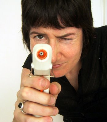 Woman holding a hot glue gun aiming at the camera.