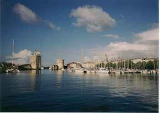 Two towers guarding harbour entrance, boats under wild sky