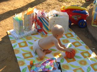 Matthew playing with a small basketball on a mat with other presents
