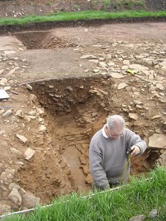 archeologist measuring the depth of the ditch