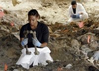 Forensic experts Sharna Daley of London, front left, examines two bones to find out whether they belong to the same person during exhumation at the mass grave site in the village of Kamenica, in the outskirts of the eastern Bosnian town of Zvornik, 120 kms north of Sarajevo on Wednesday, July 5, 2006. The mass grave in Kamenica is considered to be a secondary mass-grave, where bodies initially buried elsewhere were dumped, and containing around 300 bodies of Srebrenica massacre civilians. (AP Photo/Amel Emric)