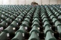 A man searches through more than 600 coffins with remains of victims of Srebrenica massacre waiting for the funeral in a factory hall in Potocari on July 11, 2005. REUTERS/Danilo Krstanovic