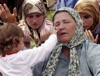A child wipes the tears of its grandmother's face as trucks carrying 505 victims of the Srebrenica massacre roll down the main street of Sarajevo, Saturday, July 8, 2006. The trucks loaded with the coffins of newly identified victims of Europe's worst massacre since World War II stopped for a few moments in Sarajevo on Saturday to allow hundreds of people to pay tribute to their beloved ones. The bodies will be buried at Srebrenica on the 11th anniversary of the massacre on Tuesday. (AP Photo/Hidajet Delic)(AP Photo/Hidajet Delic)