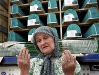 Rejha Ademovic, 60, a Bosnian Muslim woman from the eastern Bosnian town of Srebrenica, prays Saturday, July 8, 2006, in Sarajevo, in front of the truck carrying the remains of victims, among them her 15-year old son, killed in 1995 in a massacre. The trucks loaded with the coffins of 505 newly identified victims of Europe's worst massacre since World War II stopped for a few moments in Sarajevo on Saturday to allow hundreds of people to pay tribute to their beloved ones. The bodies will be buried at Srebrenica on the 11th anniversary of the massacre on Tuesday. (AP Photo/Hidajet Delic)