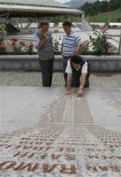 Unidentified Bosnian Muslim man points to the name of his relative on the marble stone with 8,370 names of Srebrenica victims written on it, at the Memorial Center of Potocari, near Srebrenica, north of Bosnian capital Sarajevo, on Sunday, July 9, 2006. Newly identified bodies will be buried in Srebrenica on Tuesday (July 11th) during the 11th anniversary commemorations of the massacre. Serb troops killed over 8,000 Bosniak men and boys at Srebrenica in 1995, and most of the bodies are still missing. (AP Photo/Amel Emric)
