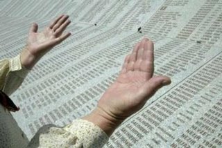 A Bosnian Muslim woman prays above a marble stone engraved with 8,370 names of Srebrenica massacre victims at the Memorial Center Potocari, near Srebrenica, July 6, 2006. About 500 identified victims of the Srebrenica massacre will be buried on its 11th anniversary on July 11, 2006. REUTERS/ Danilo Krstanovic (BOSNIA AND HERZEGOVINA)
