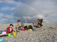 Cousins chat on the beach, with a rainbow overhead