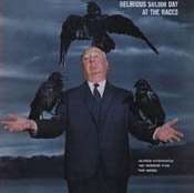 Alfred Hitchcock em pé, de terno escuro, com os braços levemente abertos, com três corvos empoleirados em seus braços e cabeça.