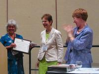 Photograph: Ann Sitkin receiving the Chapman Award from Janice Shull while outgoing TS Chair Cindy May looks on.