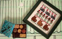 Dolls' house miniature tin of assorted biscuits and cross-stitched sampler on a sketch of a bay villa roof.