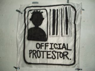Photo of a spray painted Official Protester sign, containing a bar code under which is written G82005 NO2ID