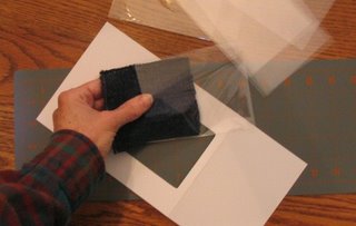 Placing a handwoven fabric sample in a plastic sleeve.