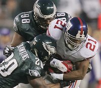 The Giants' Tiki Barber can't shake off the Eagles' Brian Dawkins and Mike Patterson. (AP)