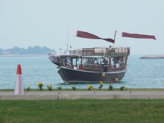 A dhow passes by, with national flags fluttering proudly