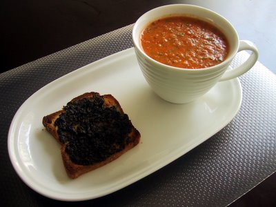 Large cup of tomato soup and toast on a plate. Underneath is a plastic placement.