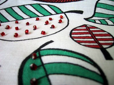 Close up of a length of black and white IKEA fabric, with parts coloured in and beads added.